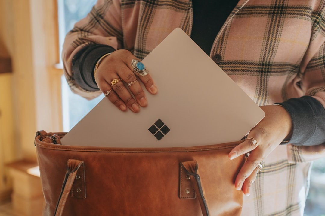 Woman putting a silver laptop in her brown tote bag