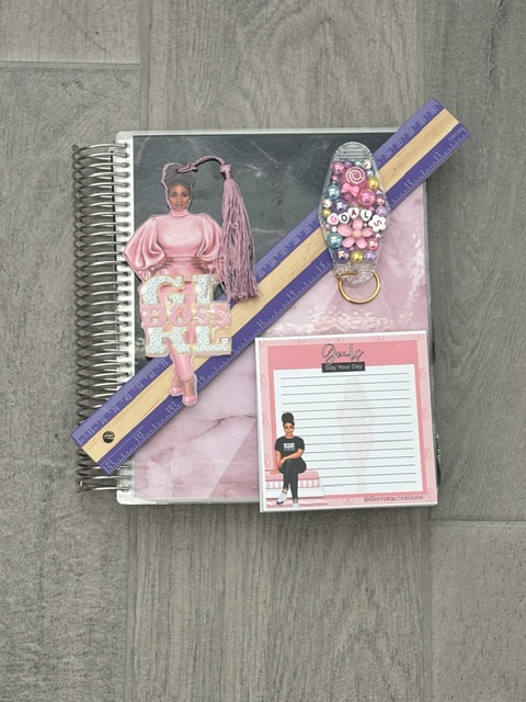 Paper planner accessories including a ruler, bookmark, paper clip, and notepad used to personalize a planner setup.