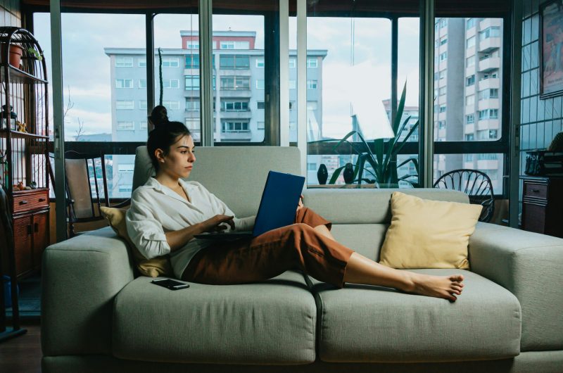 Working mom relaxing on a couch with a laptop after completing her weekday routine and reclaiming her weekend.
